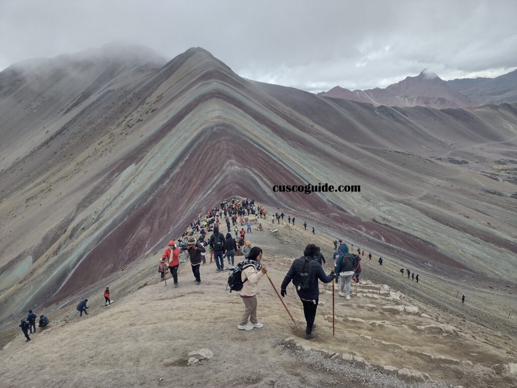 Rainbow Mountain Pass in the Andes, showcasing vibrant multicolored slopes against a clear sky in Peru. Title: